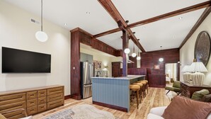 A spacious living area with a kitchen, wooden beams, a large TV, and a bar area. - Morehead City House - Loft - One bedroom suite with full kitchen and living area (Morehead City)