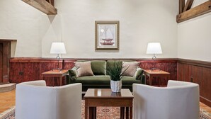 A spacious room with a green sofa, two armchairs, a coffee table, and a framed picture on the wall.