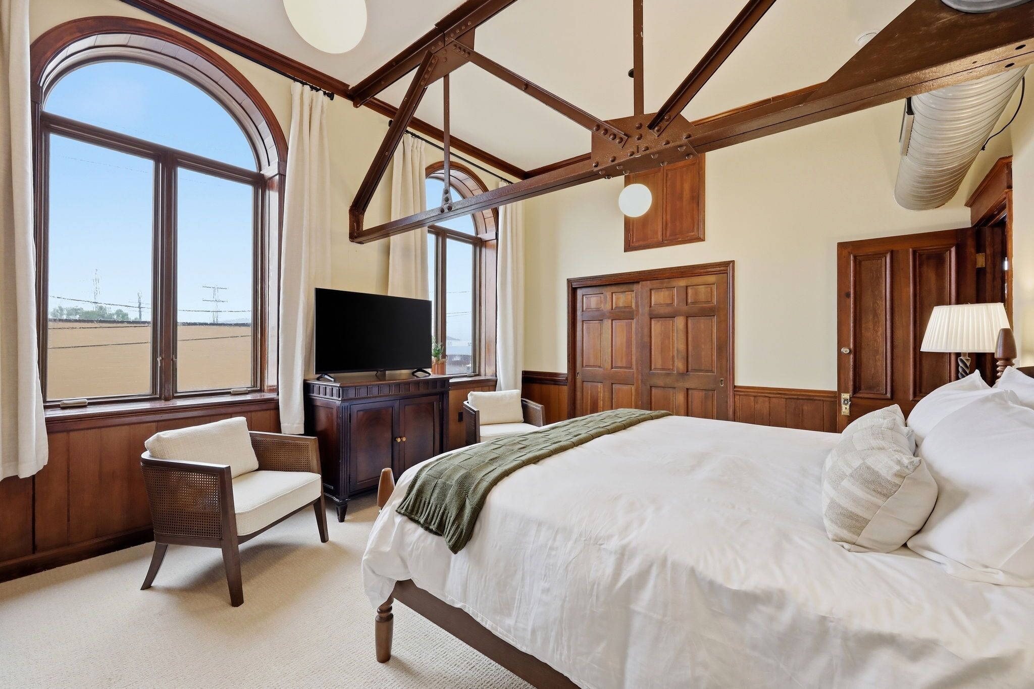 A hotel room with a large bed, a television, a desk, and a view of the beach.