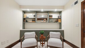 A room with two armchairs, a small table with a plant, and bookshelves above.