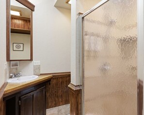 Une salle de bain avec un meuble-lavabo en bois, un évier, un miroir et un espace douche.