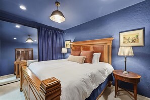 Une chambre à coucher avec un grand lit, une tête de lit en bois et une table de chevet avec une lampe.