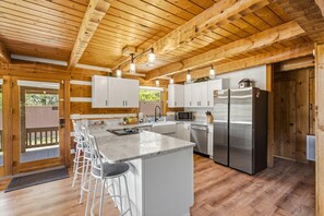 Your fully equipped kitchen glows with natural warmth from vaulted wood ceilings and exposed beams. Gather around the spacious island with stainless appliances and modern conveniences at your fingertips. - Douglas Lakefront Cabin, Boat Ramp, Private Dock, Hot Tub! (Sevierville)