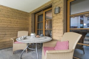 A wooden-paneled room with a round table and two wicker chairs, one with a checkered cushion. - Holiday apartment in Oberstdorf with sauna (Oberstdorf)