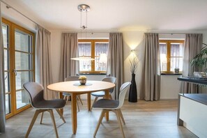 A modern dining area with a round table, four chairs, and a vase with flowers. - Holiday apartment in Oberstdorf with sauna (Oberstdorf)