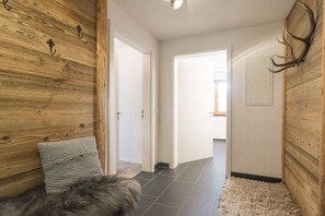 A hallway with wooden walls, a fur rug, and a deer antler decoration. - Holiday apartment in Oberstdorf with sauna (Oberstdorf)