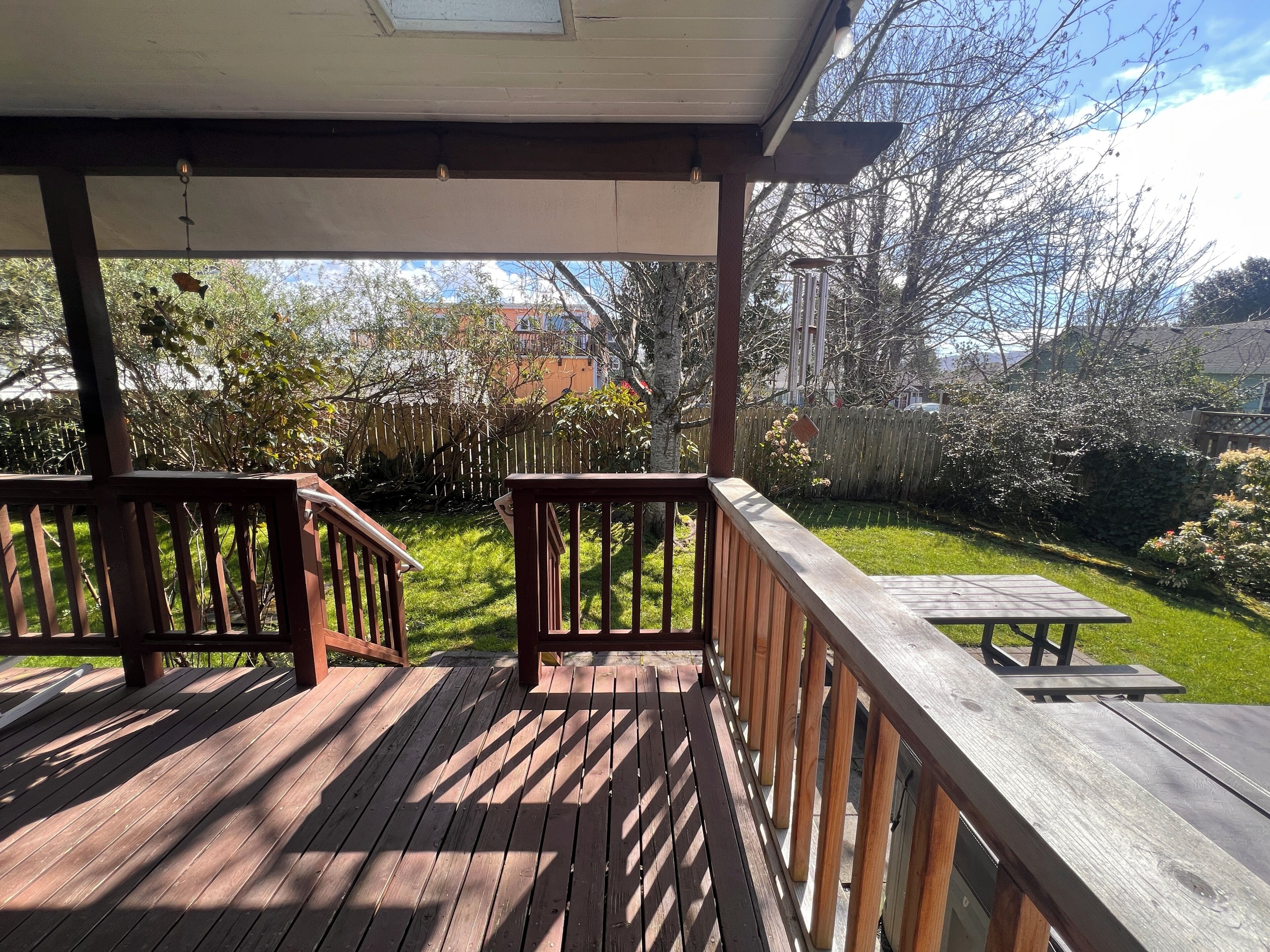 A wooden deck with a picnic table and a covered area.