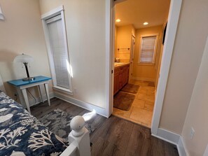 Un dormitorio con cama, mesita de noche, lámpara y ventana con persianas.