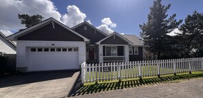 Een twee verdiepingen tellend huis met een witte garage en een veranda.