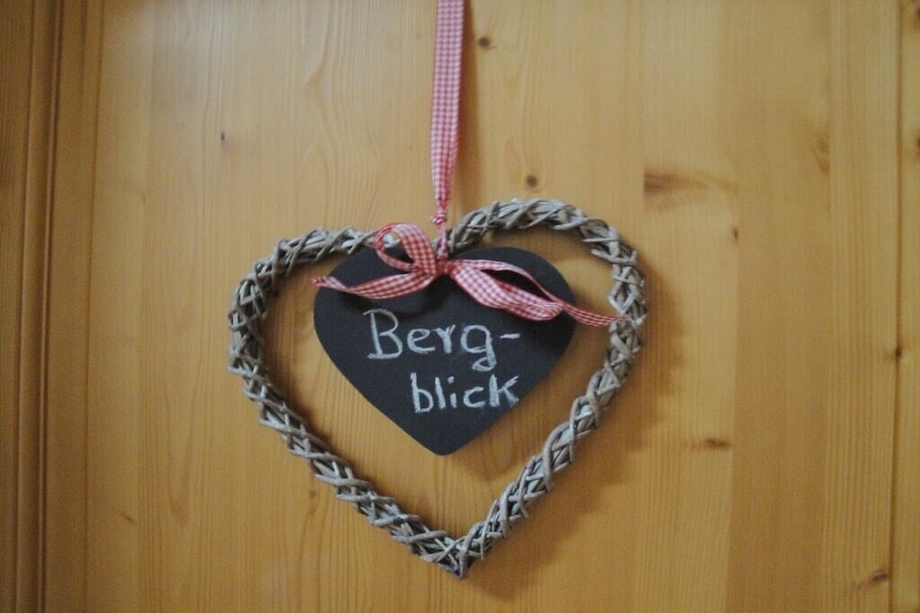 A heart-shaped decoration with the words 'Berg-blick' on a wooden door.