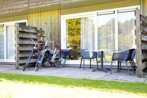 Eine Holzhütte mit einer Terrasse, Fahrrädern und Sitzgelegenheiten im Freien.