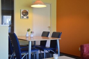 A dining area with a table, chairs, a clock, and a vase with flowers. - Apartment with 1 bedroom (Hollum Ameland)