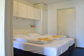 Habitación de hotel con dos camas, un armario y una puerta.