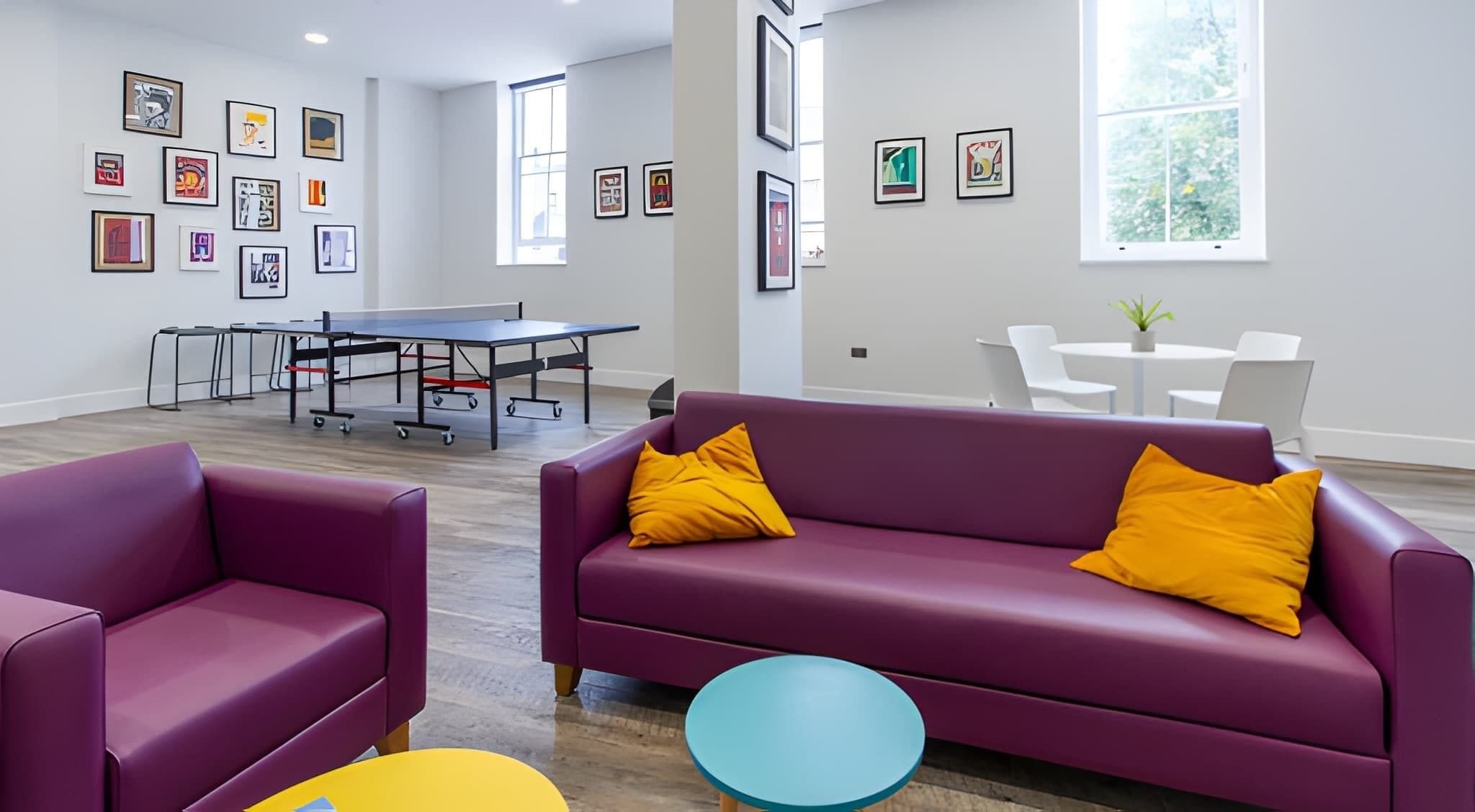 A modern interior with a purple sofa, a yellow pillow, and a blue table.