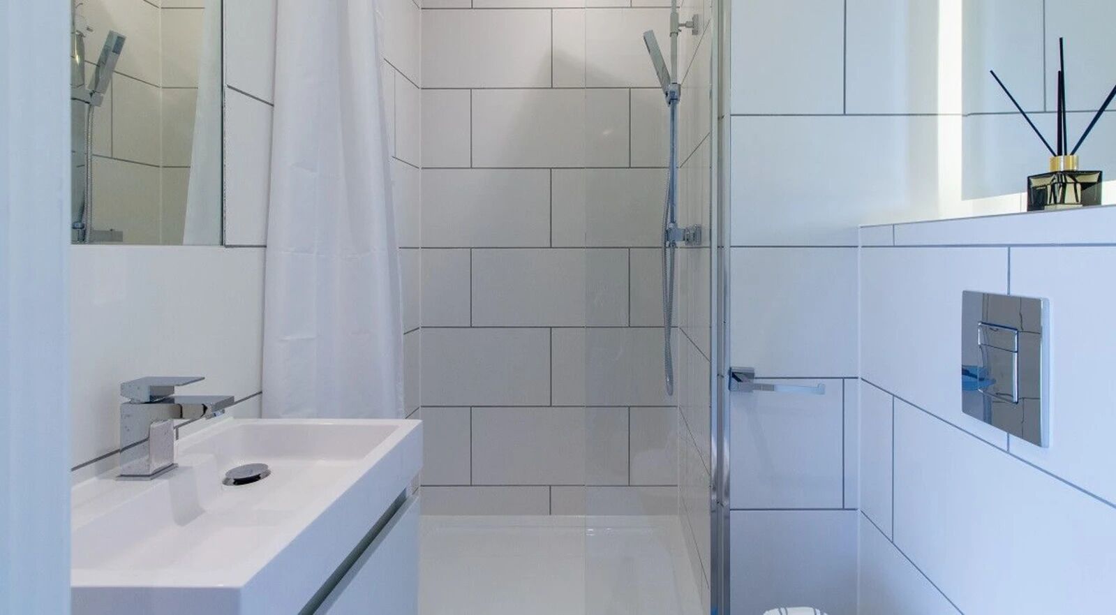 Un baño moderno con ducha, lavamanos y espejo.