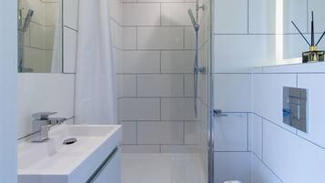 Un baño moderno con ducha, lavamanos y espejo.