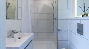 A modern bathroom with a shower, a sink, and a mirror. - AXO  - Seven Sisters - London (London)