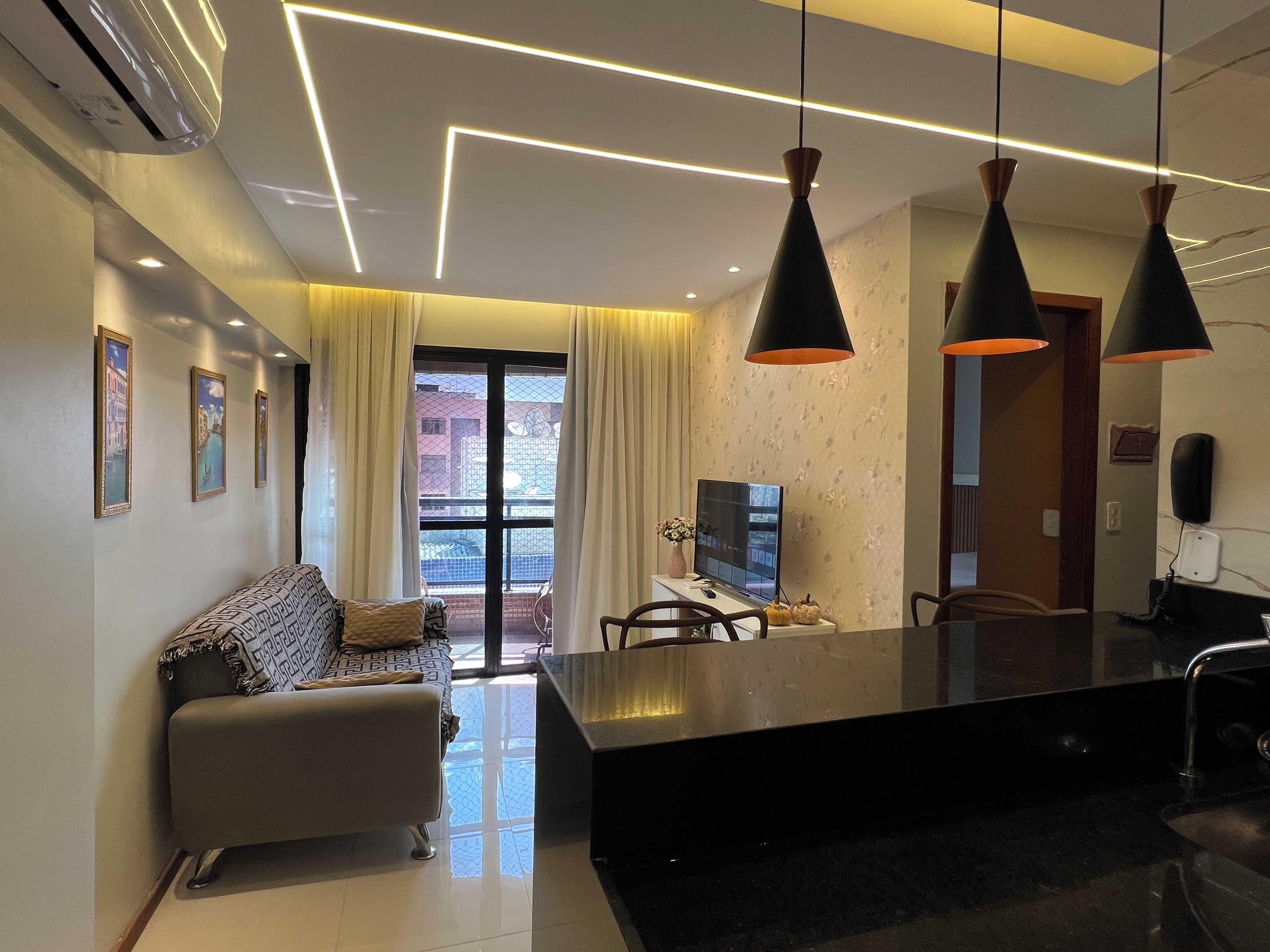Een moderne woonkamer met een bank, een flatscreen televisie en hanglampen.