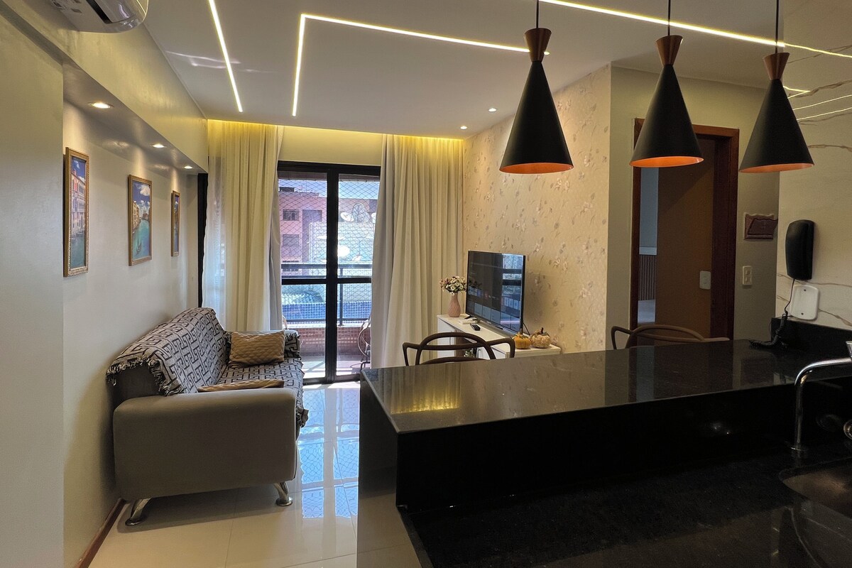 A modern living room with a sofa, a flat-screen TV, and pendant lights.