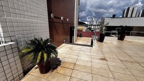 Eine Dachterrasse mit Fliesenboden, Topfpflanzen und Blick auf die Skyline der Stadt.