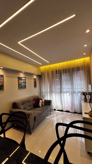 Una sala de estar moderna con un sofá, sillas, una mesa de centro y obras de arte en las paredes.