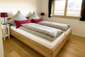 Un letto matrimoniale con cornice in legno, due comodini con lampade e una finestra con tende.