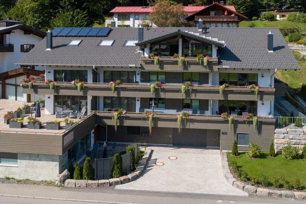 Un immeuble à plusieurs étages, doté d’un toit plat, de grandes fenêtres et d’espaces extérieurs aménagés pour s’asseoir.