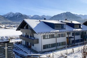 Un edificio moderno a due piani con tetto spiovente, ampie finestre e un balcone.