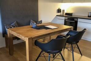 Una cucina moderna con un tavolo da pranzo in legno, sedie nere e un'isola con lavello.