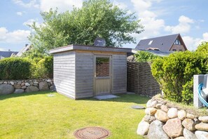 Ein kleines Holler Shed mit einer Tür, umgeben von einer Steinmauer und einem Rasen.