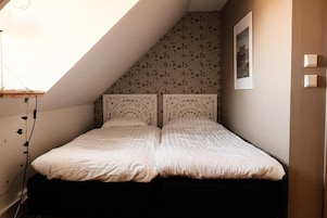 Un dormitorio con techo inclinado, una cama con cabecera y un cuadro colgado en la pared.