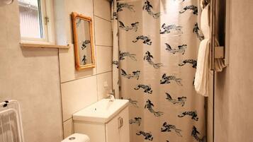 A bathroom with a toilet, sink, and shower curtain with a bird pattern.