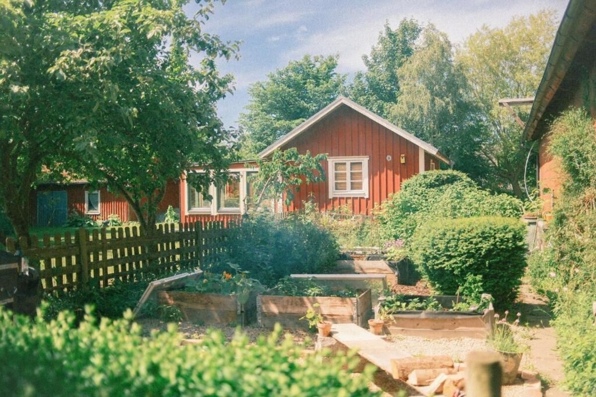 Una casa vermella de fusta amb un jardí tancat per una tanca.