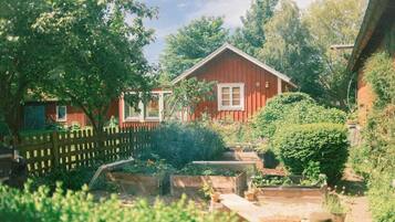 A red wooden house with a fenced garden area.