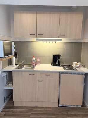A compact kitchen with a microwave, sink, and coffee maker.