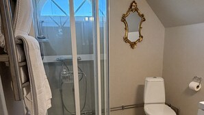 A bathroom with a glass-enclosed shower, a toilet, and a sink. - Tunnby Gårdshotell (Nyhamnsläge)