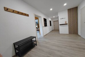 A hallway with a wooden bench, a coat rack, and a door leading to another room. - Kappes Holiday Winery 2 (Bernkastel-Kues)