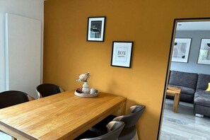A dining area with a wooden table and chairs, framed artwork on the wall, and a small decorative item on the table. - Kappes Holiday Winery 2 (Bernkastel-Kues)