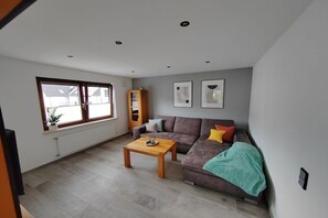 Een woonkamer met een bank, een salontafel, een radiator en een raam.