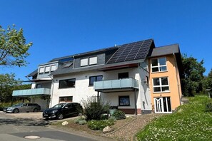 Een woonhuis met twee verdiepingen, een schuin dak, zonnepanelen, een overdekte autocarport en een tuin.
