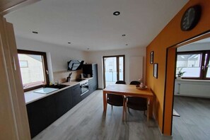 A modern kitchen with a dining area, a large window, and a clock on the wall. - Kappes Holiday Winery 2 (Bernkastel-Kues)