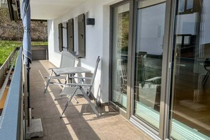 An outdoor patio with a table and chairs, a covered area, and a glass door leading to an interior space. - Holiday apartment with 2 bedrooms (Oberstdorf)