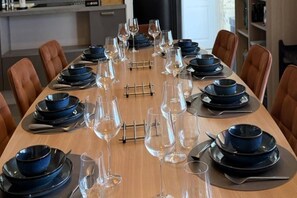 A dining table set with blue plates, clear glasses, and cutlery, surrounded by brown chairs. - Villa Rocamadour, Couzou (Couzou)