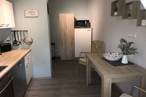 A compact kitchen with a microwave, wooden cabinets, a dining table, and a chair. - Little bit of holiday happiness (Coesfeld)