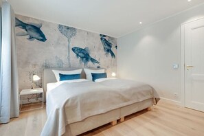 Un dormitorio con una cama, mesitas de noche y un mural de peces en la pared.