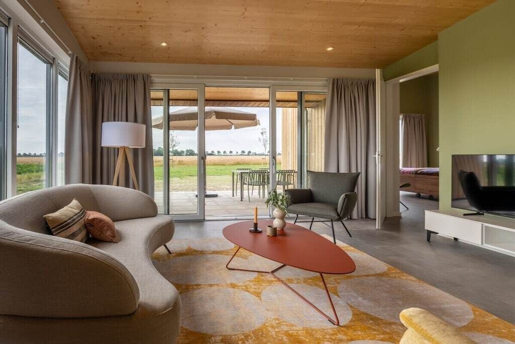 Een moderne woonkamer met een bank, een salontafel, een televisie en een schuifpui die leidt naar een buitenruimte.