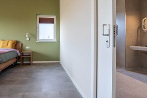 A bedroom with a bed, a bedside table, a window, and a door leading to a bathroom. - Holiday home in Zonnemaire with Wi-Fi (Zonnemaire)