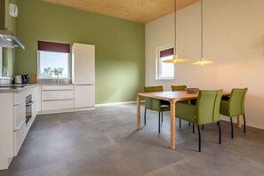 A modern kitchen with a dining area, featuring a wooden table and green chairs, under a sloped ceiling with pendant lights. - Holiday home in Zonnemaire with Wi-Fi (Zonnemaire)