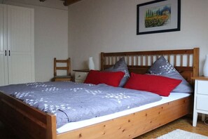 Une chambre à coucher avec un lit en bois, deux tables de chevet, une armoire blanche et un tableau accroché au mur.
