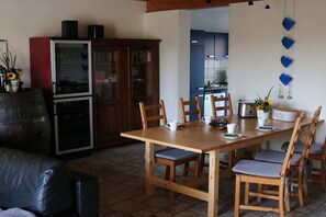 Un comedor con una mesa y sillas de madera, un refrigerador y un armario.